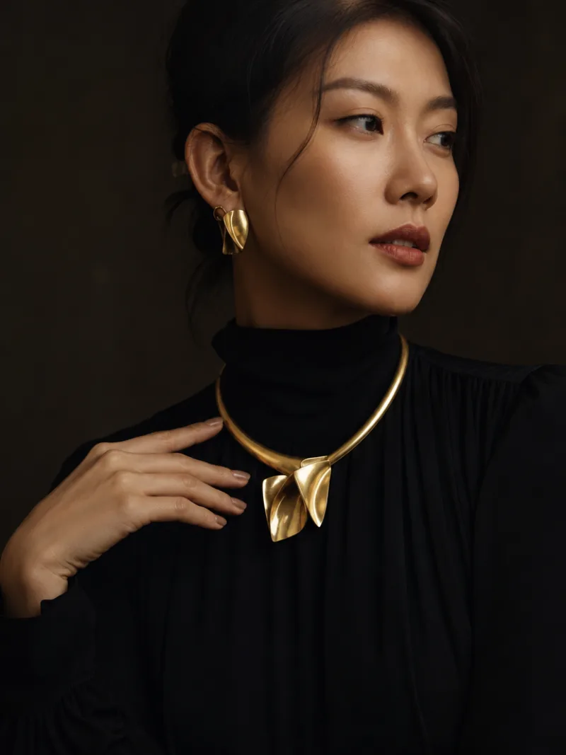 Gold necklace and earrings editorial portrait in a dark studio setting