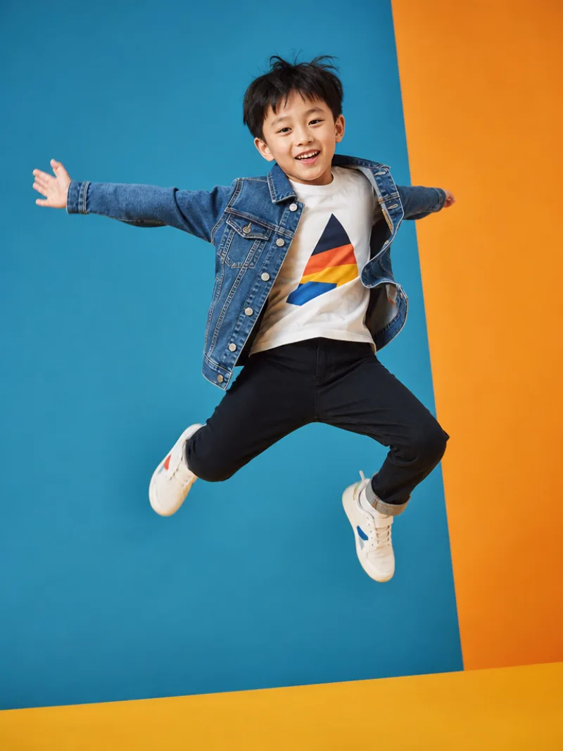 Child AI model in a denim jacket and sneakers, kidswear shot